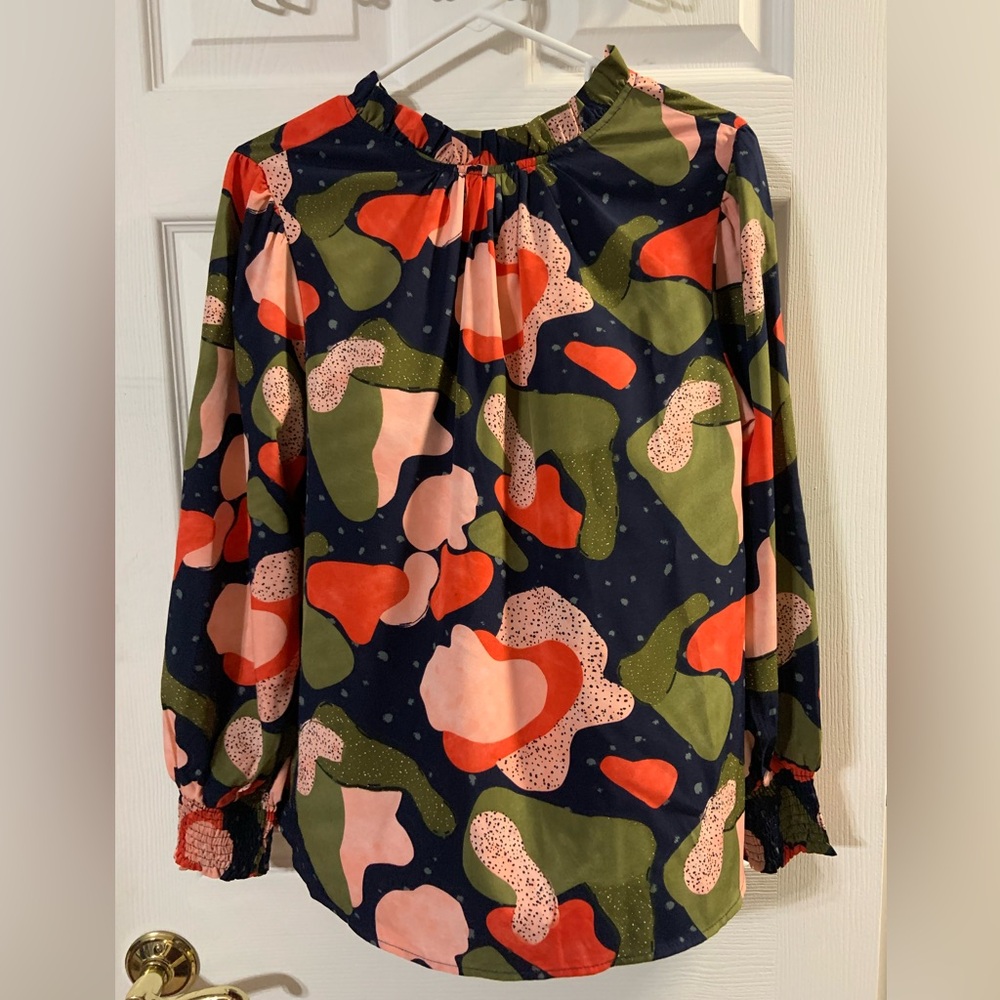 Women’s blouse with button neck and smocked sleeve detail.